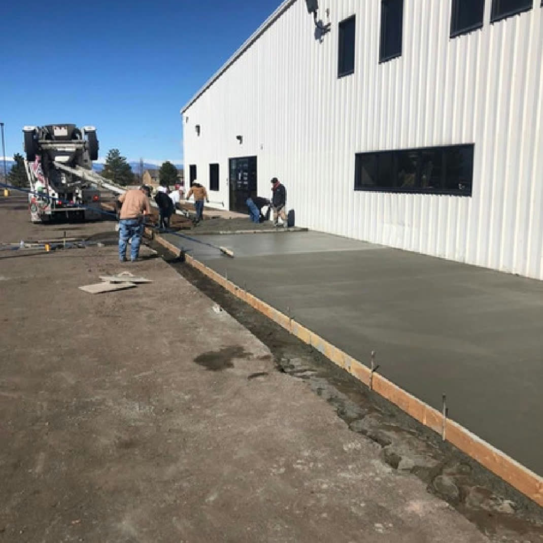 Crew pouring a commercial slab by a warehouse